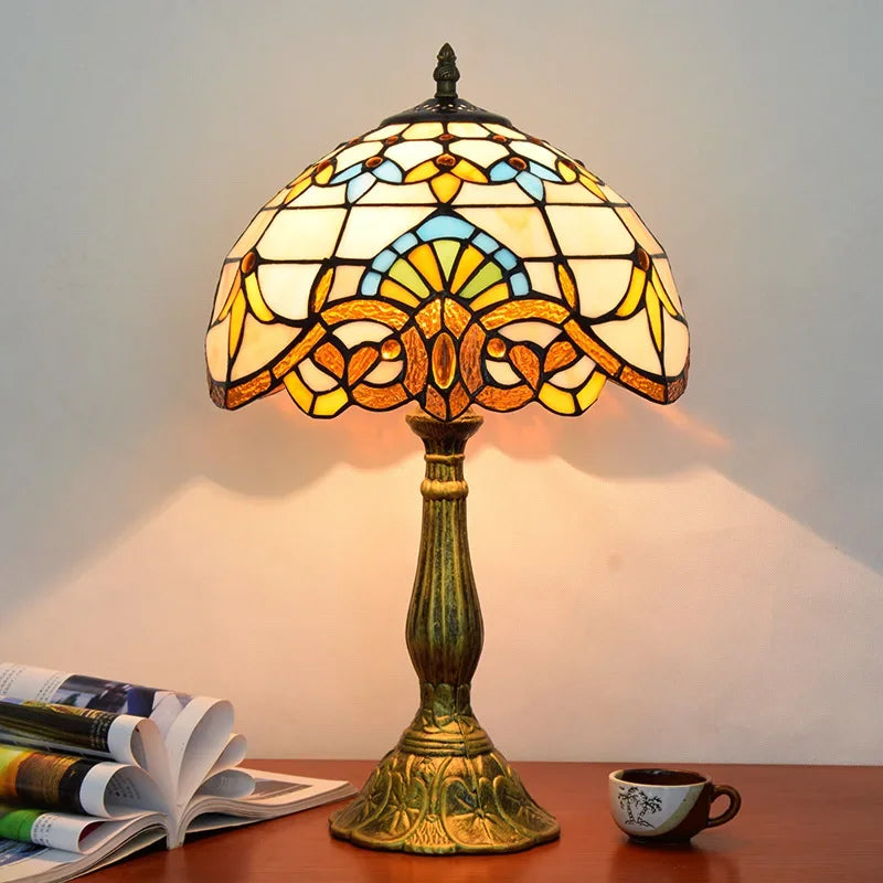 Lampada da tavolo Tiffany in bronzo antico con decorazioni floreali e vetrate colorate.